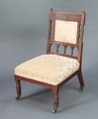 An Edwardian carved walnut nursing chair with upholstered seat and back 