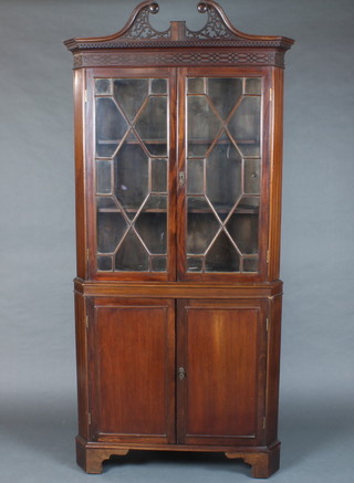 A 19th Century Chippendale style mahogany corner cabinet, the upper section with pierced broken pediment and blind fretwork frieze, with astragal glazed doors, the base fitted a cupboard enclosed by double panelled doors raised on bracket feet 82"h x 39"w x 21"d