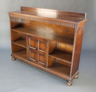 A Waring & Gillow oak bookcase with raised back, the apron with arcaded decoration fitted 1 shelf above cupboard flanked by 2 shelves, raised on bun feet 38 1/2"h x 50 1/2"w x 12"d