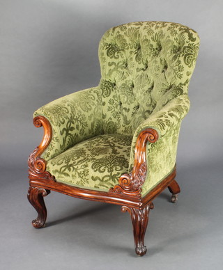 A Victorian carved rosewood show frame armchair upholstered in green button back material raised on cabriole supports