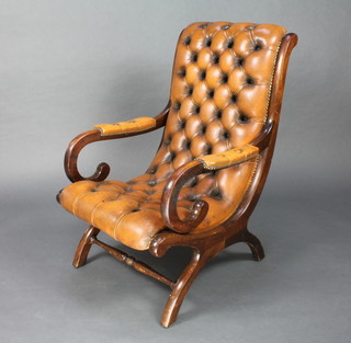 A Victorian style showframe open arm chair upholstered in brown button back leather with turned stretchers