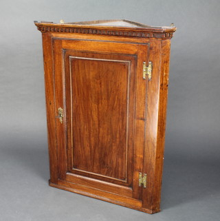 A Georgian oak hanging corner cabinet and dentil cornice, the interior fitted shelves enclosed by a panelled door with brass H shaped hinges 38"h x 29 1/2"w x 16"d