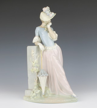 A Lladro figure of a standing lady with parasol beside a pedestal 38cm h 

