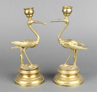 A pair of Victorian gilt metal candlesticks in the form of standing cranes, raised on circular bases 23cm h 
