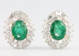 A pair of 18ct white gold emerald and diamond ear clips, the emeralds approx 6.69ct surrounded by brilliant and baguette cut diamonds approx 3.46ct