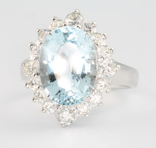 An 18ct white gold oval aquamarine and diamond cluster ring, the centre stone approx 5.25ct surrounded by brilliant cut diamonds, approx 0.77ct, size M 1/2