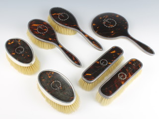 A silver and tortoiseshell pique brush set comprising hand mirror, 2 hair brushes, 2 clothes brushes and 2 gentleman's hair brushes, mixed dates Birmingham 1925/47 