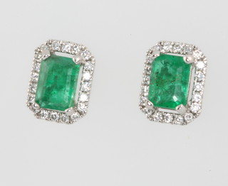 A pair of 15ct white gold emerald and diamond cluster ear studs, the emeralds approx 0.98ct surrounded by brilliant cut diamonds, approx 0.19ct