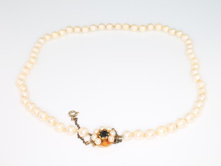 A string of cultured pearls with a 9ct yellow gold, garnet and pearl clasp, 15"