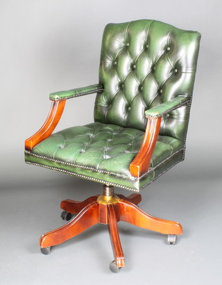 A revolving open arm office chair upholstered in green buttoned leather  