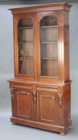 A Victorian mahogany bookcase on cabinet with moulded cornice, fitted adjustable shelves enclosed by arched panelled doors above 2 drawers and double cupboard enclosed by panelled doors 91 1/2"h x 48 1/2"w x 18"d 