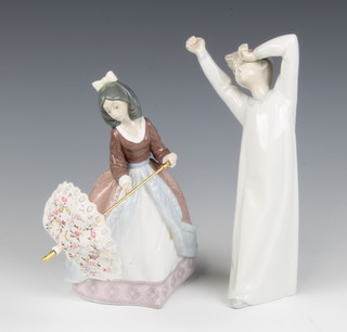 A Lladro figure of a standing boy yawning, the base impressed 4870 23cm h and 1 other Lladro figure of a standing lady with parasol impressed 5210  20cm 