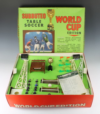 A Subbuteo World Champion edition football game, the top tray fitted 2 floodlights, scoreboard, World Cup, 6 flags, 2 goals, 2 teams, 2 nets and 1 ball (1 ball and half time scoreboard missing), the lower tray fitted team, target board, 2 small sections of fence surround, club flag, TV tower, TV camera (cameraman missing), TV monitor/commentator, referee and 2 linesmen, manager and trainer, 4 press photographers and whistle - the playing cloth is missing and the box is slightly bent, together with a Subbuteo table soccer elementary playing instructions and rules, advanced Subbuteo table 1969/70, do. price list 1969/70, do. Subbuteo hand book 1974 and a 1974/75 catalogue 