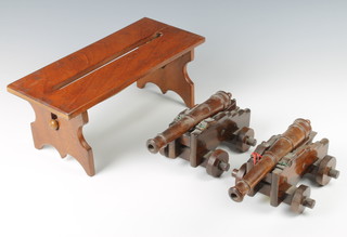 A pair of turned rosewood cannons raised on stepped trunnions 10cm x 25cm x 15cm together with a mahogany folding stool 15cm x 32cm x 34cm 
