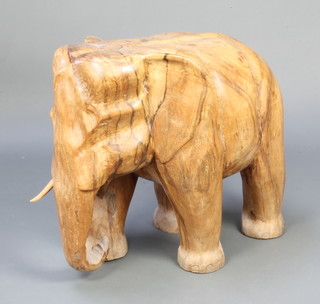 A carved hardwood figure of a standing elephant 60cm h x 70cm w x 40cm d, there are slight splits to the body and 1 tusk is missing 