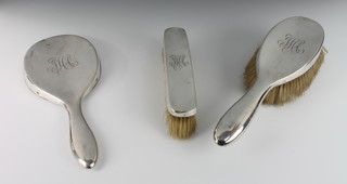 A silver 3 piece dressing table set comprising hand mirror, clothes brush and hair brush, London 1911 and London 1919 
