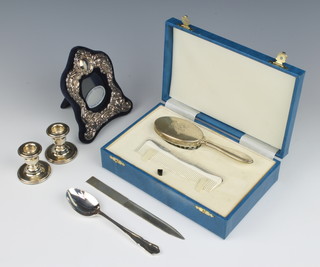 A baby's sterling silver brush and comb, a pair of dwarf candlesticks, paper knife, repousse photograph frame and spoon 