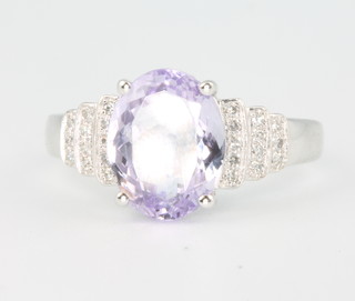 A 14ct white gold oval tanzanite and diamond ring, the centre stone approx. 3.75ct flanked by brilliant cut diamonds in a stepped mount approx. 0.65ct size M 1/2