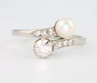 An Edwardian white gold pearl and diamond cross-over ring, the brilliant cut diamond approx. 0.5ct the cultured pearl approx. 5.5mm, size P 