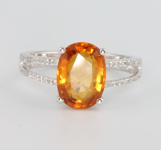 A 14ct white gold oval yellow sapphire and diamond ring, the centre stone approx. 4.2ct, the open shank set with brilliant cut diamonds approx. 0.25ct size M 