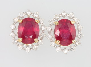 A pair of 18ct white white gold oval ruby and diamond cluster earrings, the rubies approx 4.65ct, the brilliant cut diamonds approx. 0.43ct
