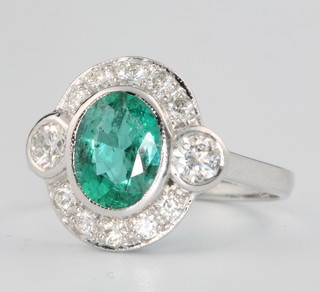 An 18ct white gold oval emerald and diamond cluster ring, the centre stone approx. 1.5ct surrounded by brilliant cut diamonds approx. 0.75ct size N 1/2