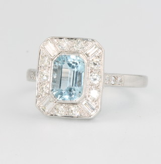 An 18ct white gold Art Deco style aquamarine and diamond ring, the centre stone approx. 1.0ct surrounded by 10 brilliant cut diamonds and 4 baguette cut diamonds, size O 1/2