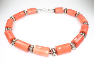 An African silver and coral necklace comprising 12 cylindrical column coral beads interspersed with 11 silver roundels, 59cm 