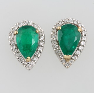 A pair of white gold pear cut emerald and diamond ear studs, the emeralds approx. 1.25ct each surrounded by brilliant cut diamonds 