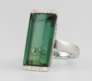 An 18ct white gold rectangular tourmaline and diamond ring, the rectangular cut stone  22mm x 10mm flanked by 6 brilliant cut diamonds size 0 1/2
