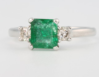 An 18ct white gold square cut emerald and diamond ring, the centre stone approx. 0.94ct flanked by 2 brilliant cut diamonds approx. 0.22ct, size M 