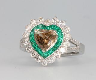 An 18ct white gold heart shaped diamond and emerald ring, the centre heart shaped diamond approx. 1.22ct surrounded by emeralds approx 1.89ct surrounded by brilliant cut diamonds approx. 0.98ct, size O