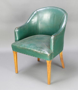 A tub back armchair upholstered in green leather raised on chamfered supports 