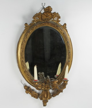 A 19th Century oval bevelled plate wall mirror contained in a decorative gilt frame and 3 having light candle sconces to the base 76cm h x 46cm w 