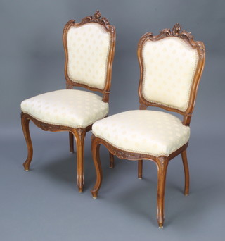 A pair of Victorian French carved walnut show frame dining chairs with upholstered seats and backs raised on cabriole supports 