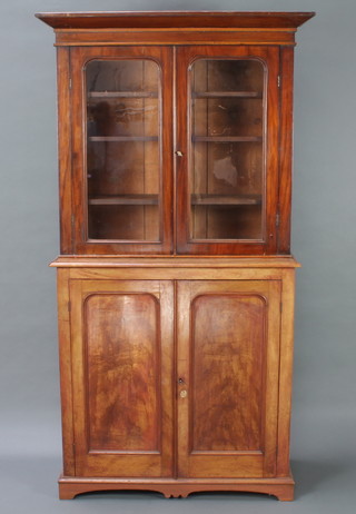 A Victorian mahogany bookcase on cabinet the upper section with moulded cornice, the interior fitted shelves enclosed by arched glazed panelled doors, the base enclosed by arched panelled doors 194cm h x 96cm w x 42cm d 