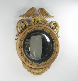 A Regency circular convex plate wall mirror contained in a gilt ball studded frame surmounted by a figure of an eagle with wings outstretched 