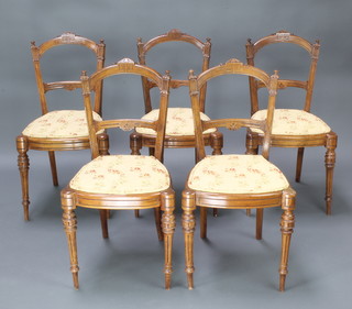 A set of 6 Edwardian carved walnut rail back dining chairs with carved mid rails, raised on turned and fluted supports