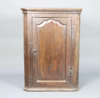 An 18th Century oak hanging corner cabinet with moulded cornice, the interior fitted shelves enclosed by an arched panelled door 97cm h x 70cm w x 39cm d 