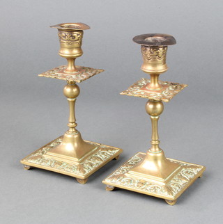 A pair of Victorian brass candlesticks raised on square bases with cast mask decoration and detachable sconces 17cm x 9cm x 8cm 