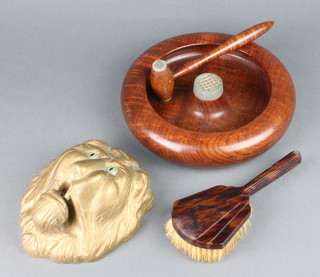 A circular turned wooden nut bowl complete with gavel 5cm x 24cm, a carved and gilt painted wooden lion mask, the reverse marked rescued from a bonfire in the Tower of London 1942 7cm x 15cm x 18cm together with an Art Deco simulated tortoiseshell hairbrush  