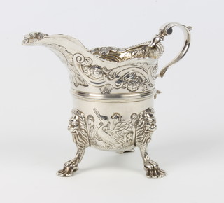 A cast silver cream jug with armorial scroll, flowers, lion knees and paw feet 13cm, 282 grams