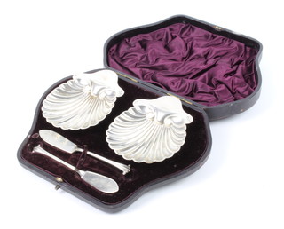 A cased pair of Victorian shell shaped butter dishes and knives in a fitted case London 1894, maker Josiah Williams & Co 112 grams 