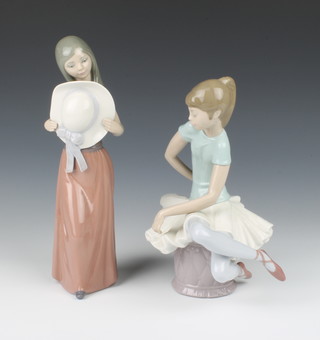 A Lladro figure of a ballerina sitting on a pouffe 20cm, a do. of a young lady holding a hat 25cm 