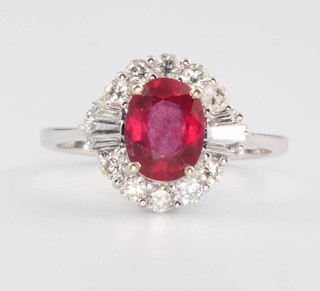 An 18ct white gold ruby and diamond oval cluster ring, the ruby approx 1.8ct flanked by tapered baguette and brilliant cut diamonds 0.58ct, size O 