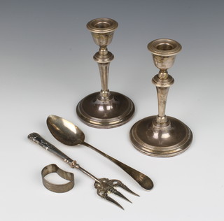 A pair of silver candlesticks, rubbed marks, a spoon, fork and napkin ring