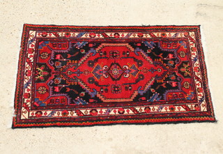A red and blue ground Persian rug with central medallion and multi-row border 130cm x 77cm 