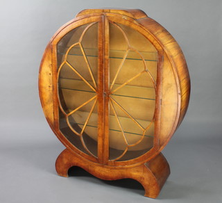 A 1930's Art Deco circular figured walnut display cabinet, fitted shelves enclosed by a stylised sunburst astragal glazed panelled door, raised on scroll supports 137cm h x 111cm d x 30cm w 


