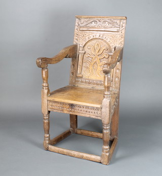 A 17/18th Century carved oak Wainscot chair with arched carved panel to the back and solid seat, the apron heavily carved throughout, raised on turned and block supports, the back panel marked "1672 H R M" 106cm h x 46cm w x 43cm d