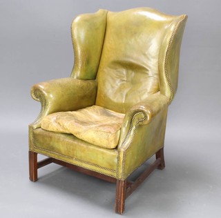 A Georgian style mahogany wing armchair upholstered in green leather 